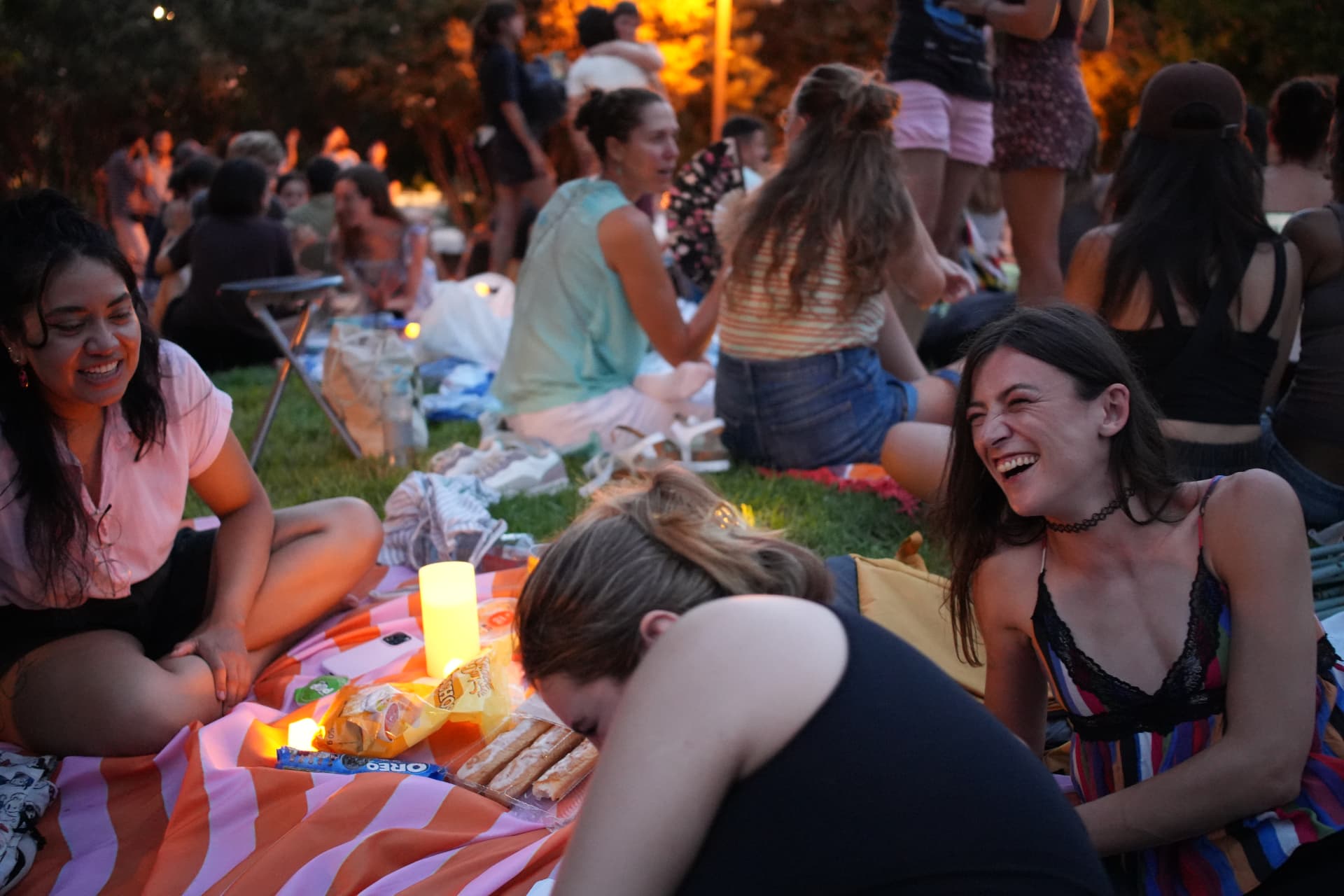 Invitados de GoBundl riendo sobre una manta de picnic en un concierto al aire libre en Valencia
